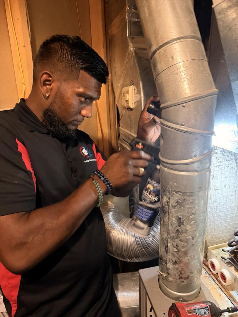 Josh inspecting a furnace flue pipe in a basement